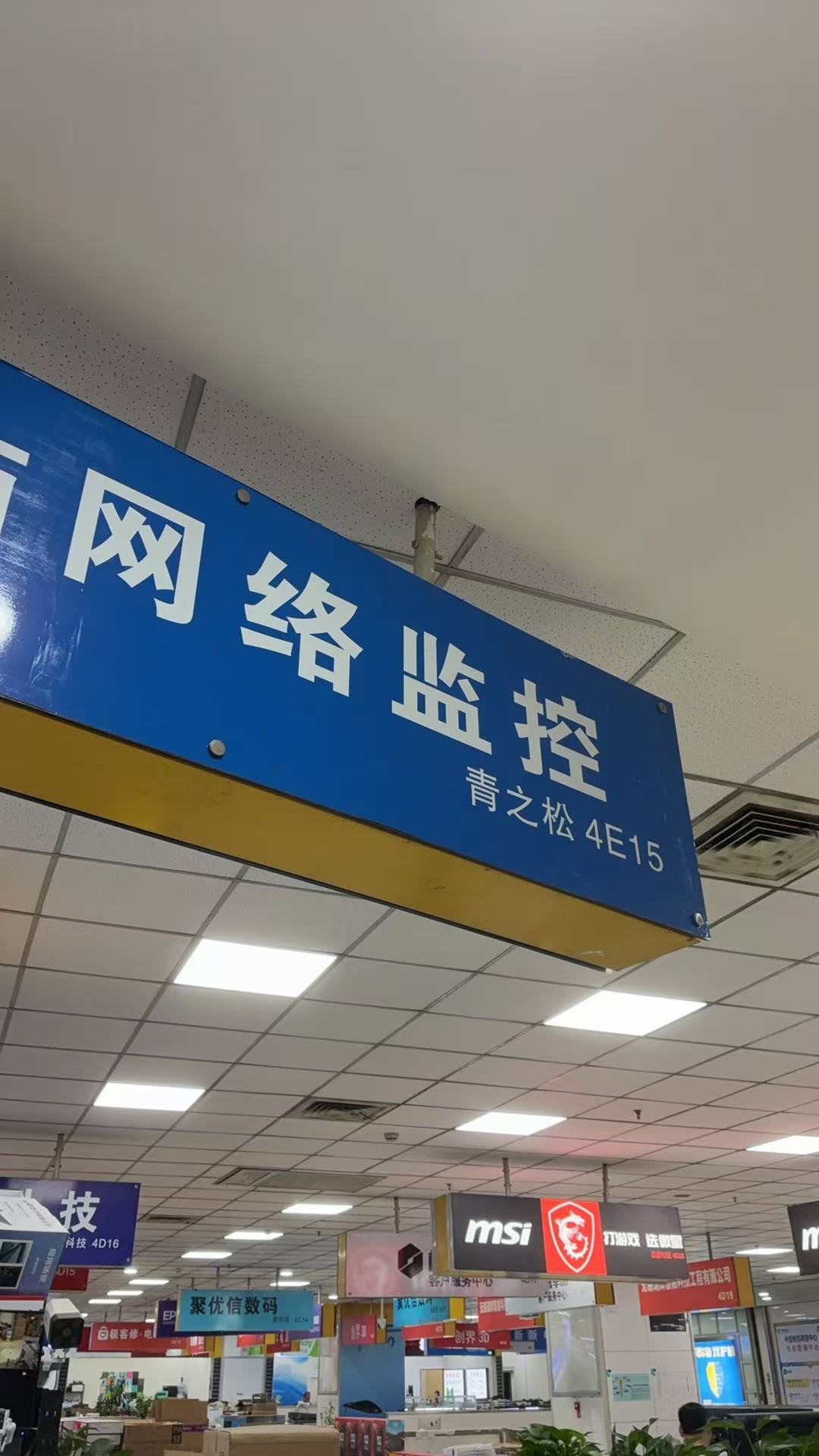 青之松门店货架特写 - 多层展示柜陈列海康威视监控摄像头、萤石网络摄像机、录像机等安防设备，以及锐捷交换机、TP-LINK 路由器等网络设备